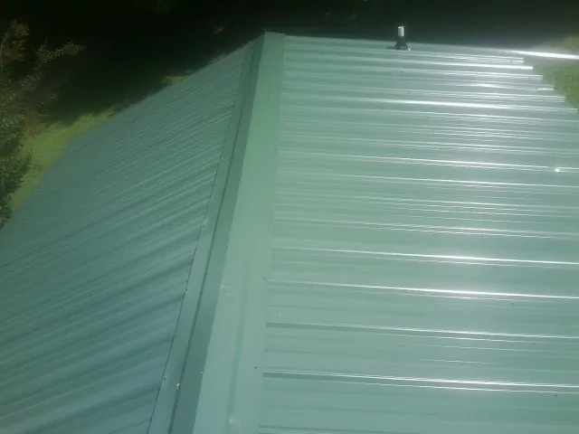New green metal panels meeting at the ridge of a roof — Flat Roof Repair work by our crew in Fontana